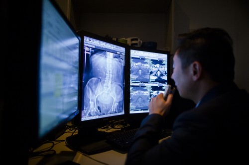 Radiologist sits at desk dictating notes as he reviews a radiology scan