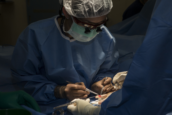 A surgeon sutures a hand injury.