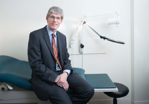 Prof Kit Fairley sitting on a bed in the clinic