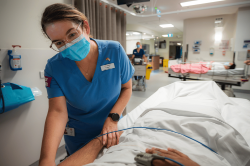 Female nurse tending to patient in bed