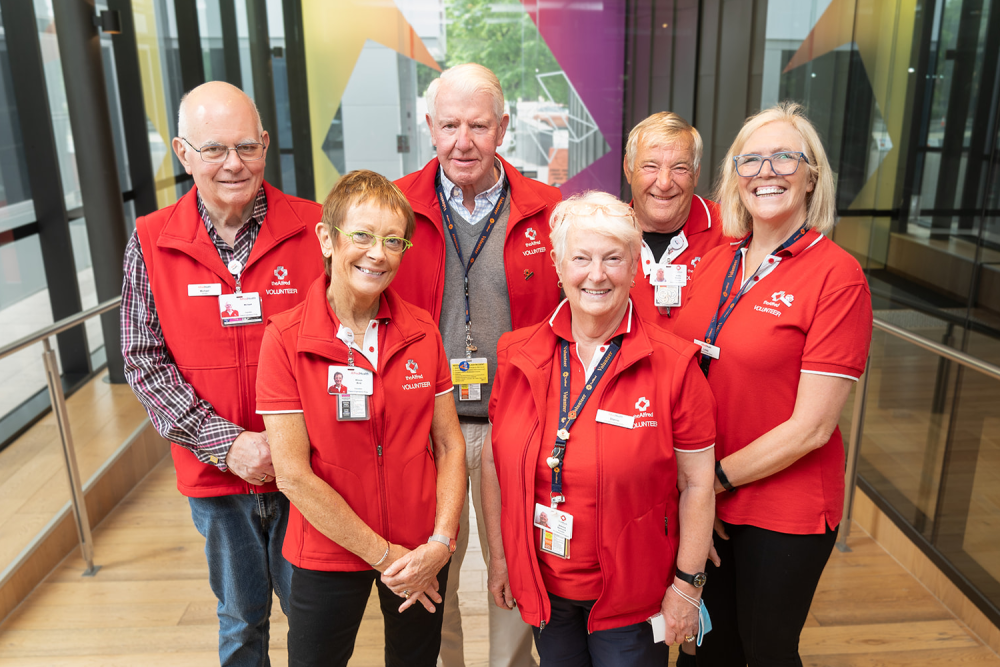 Group of volunteers facing camera wearing red uniforms