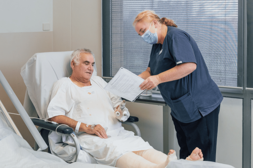 Male patient with bandages seated with nurse showing information sheet