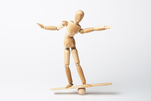 wooden figure balanced on balance board